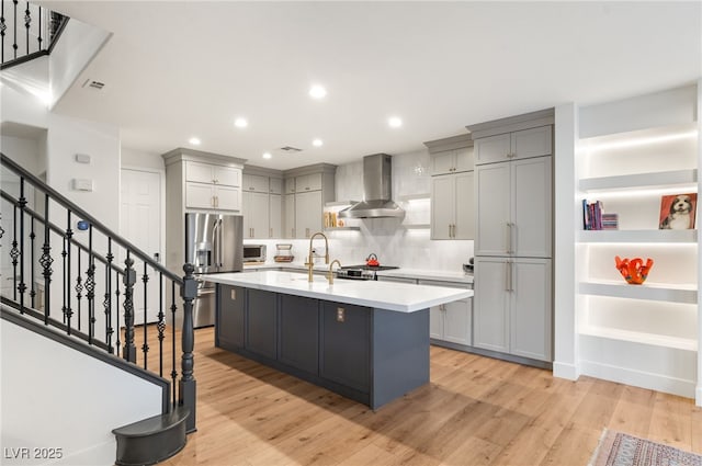 2310 Malaga Peak St, Las Vegas, NV 89135 - kitchen featuring appliances with stainless steel finishes, wall chimney exhaust hood, gray cabinets, light countertops, and light wood-type flooring