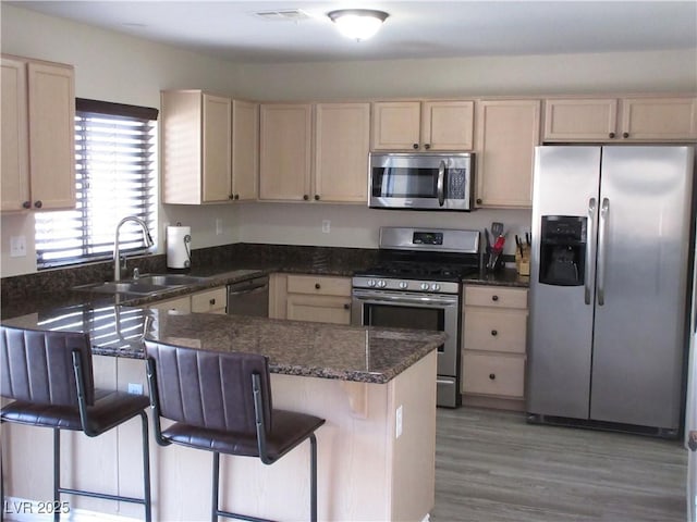 10013 Solid Lime St, Las Vegas, NV 89183 - kitchen featuring appliances with stainless steel finishes, light brown cabinets, a kitchen breakfast bar, light wood-style floors, and a peninsula