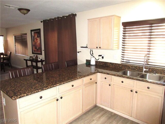 10013 Solid Lime St, Las Vegas, NV 89183 - kitchen featuring a peninsula, light wood finished floors, and dark stone counters