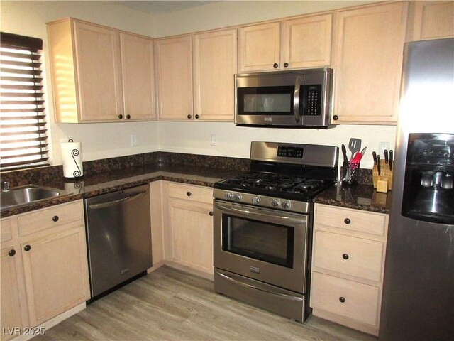 10013 Solid Lime St, Las Vegas, NV 89183 - kitchen featuring stainless steel appliances, light brown cabinets, light wood-style floors, and dark stone countertops