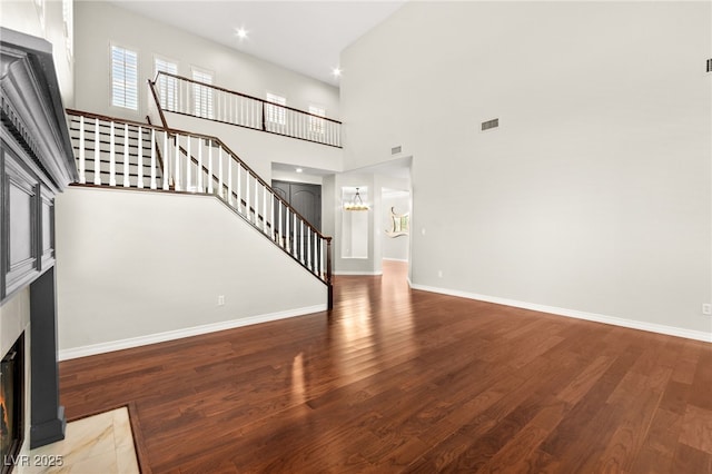 1800 Aztec Cliffs Ct, Las Vegas, NV 89128 - unfurnished living room featuring a fireplace, stairs, wood finished floors, a high ceiling, and a chandelier