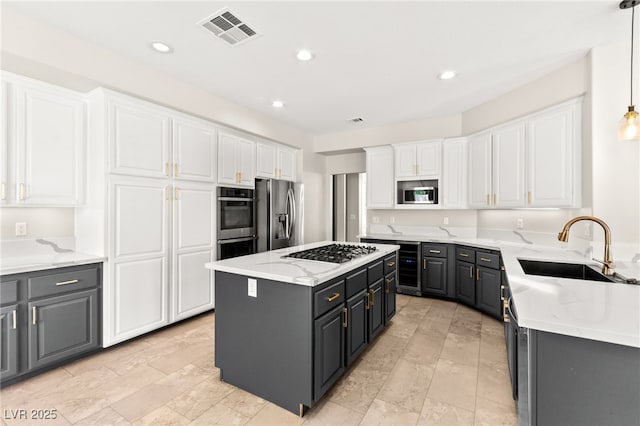 1800 Aztec Cliffs Ct, Las Vegas, NV 89128 - kitchen featuring stainless steel appliances, white cabinetry, a center island, light stone countertops, and gray cabinets