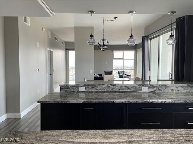150 Las Vegas Blvd Unit 1115, Las Vegas, NV 89101 - kitchen with dark cabinetry, dark stone countertops, wood finished floors, hanging light fixtures, and open floor plan
