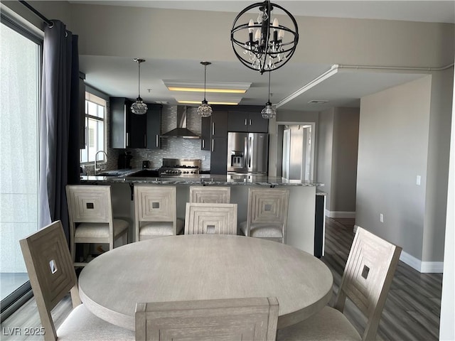 150 Las Vegas Blvd Unit 1115, Las Vegas, NV 89101 - kitchen with stainless steel refrigerator with ice dispenser, wall chimney range hood, a raised ceiling, wood finished floors, and decorative backsplash