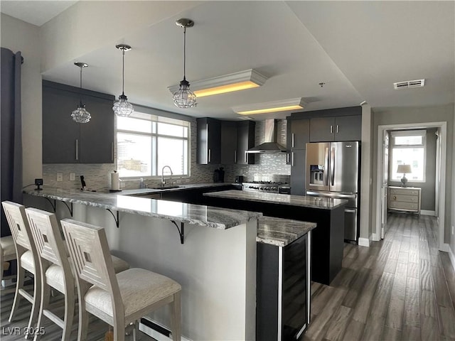 150 Las Vegas Blvd Unit 1115, Las Vegas, NV 89101 - kitchen featuring stainless steel refrigerator with ice dispenser, wall chimney range hood, a peninsula, backsplash, and a breakfast bar area