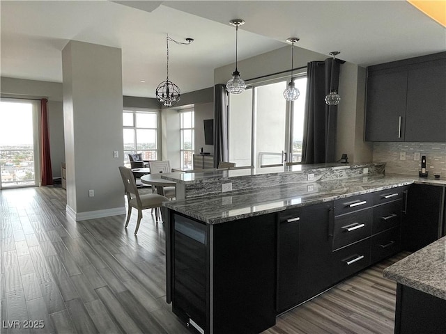 150 Las Vegas Blvd Unit 1115, Las Vegas, NV 89101 - kitchen featuring dark cabinets, tasteful backsplash, hanging light fixtures, a peninsula, and wood finished floors