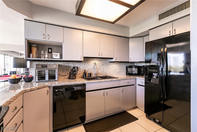 3111 Bel Air Dr Unit 9E, Las Vegas, NV 89109 - kitchen with black appliances, decorative backsplash, open shelves, light tile patterned floors, and light stone counters