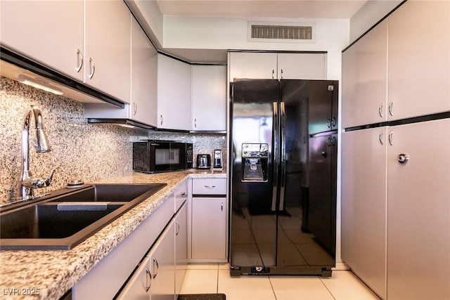 3111 Bel Air Dr Unit 9E, Las Vegas, NV 89109 - kitchen featuring black appliances, decorative backsplash, light tile patterned floors, and white cabinetry