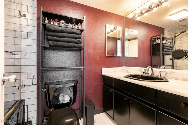 3111 Bel Air Dr Unit 9E, Las Vegas, NV 89109 - bathroom with a textured wall, vanity, and a tile shower