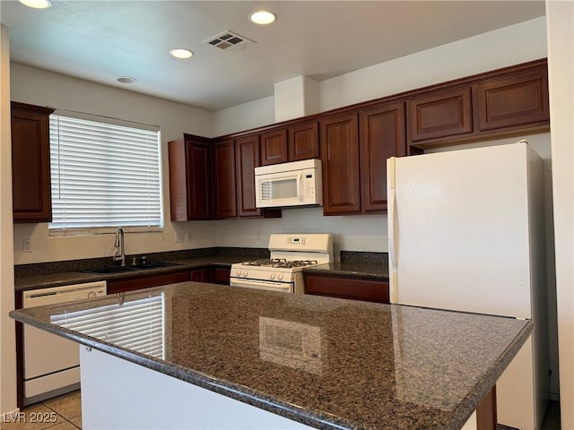 5905 Addy Ln, North Las Vegas, NV 89081 - kitchen with white appliances, recessed lighting, a center island, dark stone counters, and light tile patterned flooring