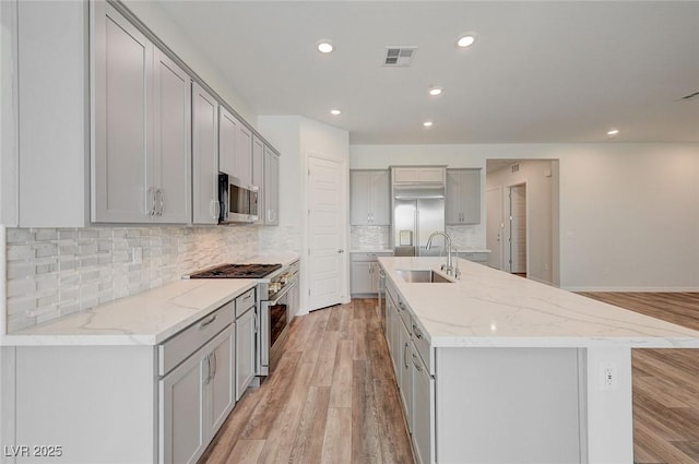 12436 Primrose Grove Ln, Las Vegas, NV 89138 - kitchen featuring appliances with stainless steel finishes, gray cabinetry, light wood finished floors, an island with sink, and recessed lighting