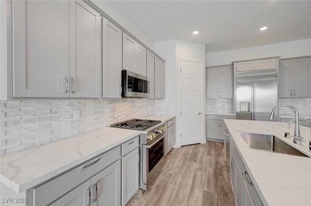 12436 Primrose Grove Ln, Las Vegas, NV 89138 - kitchen with premium appliances, gray cabinets, tasteful backsplash, light wood-type flooring, and recessed lighting