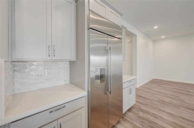 12436 Primrose Grove Ln, Las Vegas, NV 89138 - kitchen with stainless steel built in fridge, tasteful backsplash, light wood-style floors, light stone countertops, and recessed lighting