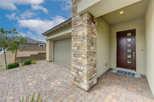 12436 Primrose Grove Ln, Las Vegas, NV 89138 - view of exterior entry with stucco siding, decorative driveway, and an attached garage