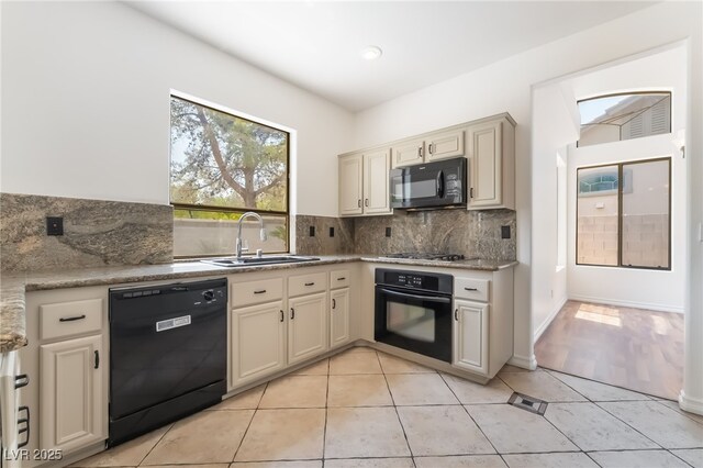 1312 Autumn Wind Way, Henderson, NV 89052 - kitchen with black appliances, decorative backsplash, cream cabinets, light tile patterned floors, and light countertops
