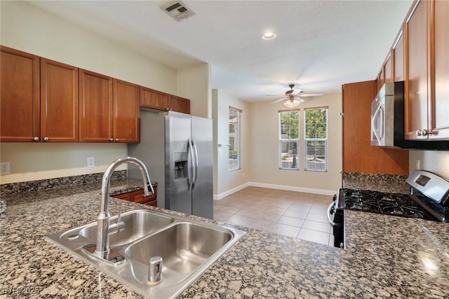 9305 Ironsend St, Las Vegas, NV 89143 - kitchen with stainless steel appliances, brown cabinets, ceiling fan, light tile patterned floors, and dark stone counters