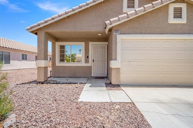 4928 Corsica Island St, North Las Vegas, NV 89031 - view of exterior entry with stucco siding, concrete driveway, a garage, and a tiled roof