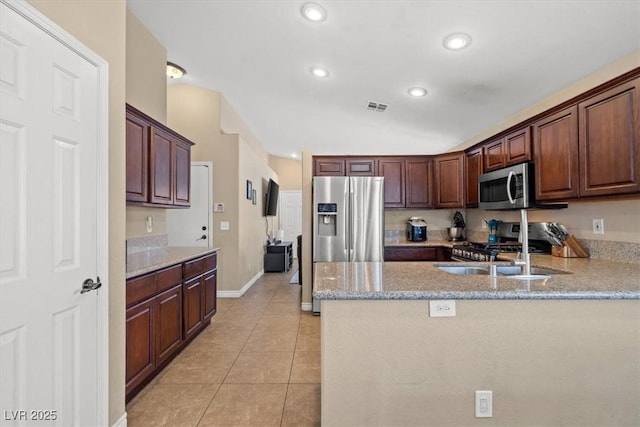 4928 Corsica Island St, North Las Vegas, NV 89031 - kitchen featuring appliances with stainless steel finishes, light tile patterned flooring, recessed lighting, a peninsula, and light stone countertops