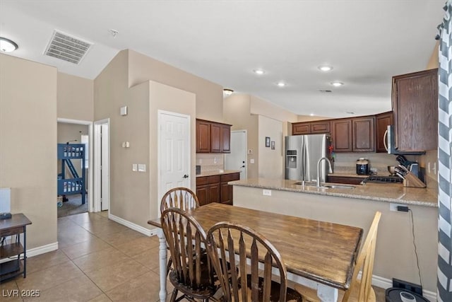 4928 Corsica Island St, North Las Vegas, NV 89031 - kitchen with stainless steel appliances, a peninsula, light tile patterned floors, recessed lighting, and light stone countertops
