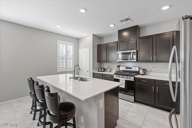 3310 Palindrome Ave, Henderson, NV 89044 - kitchen featuring appliances with stainless steel finishes, a kitchen breakfast bar, light countertops, an island with sink, and light tile patterned flooring