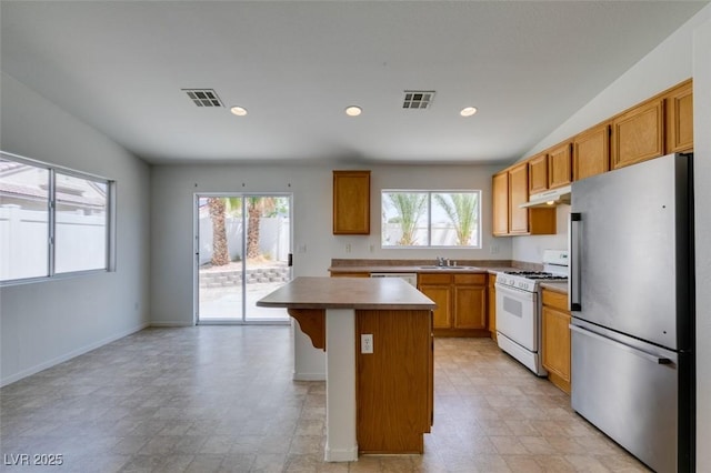 352 River Glider Ave, North Las Vegas, NV 89084 - kitchen featuring freestanding refrigerator, gas range gas stove, under cabinet range hood, a kitchen island, and recessed lighting