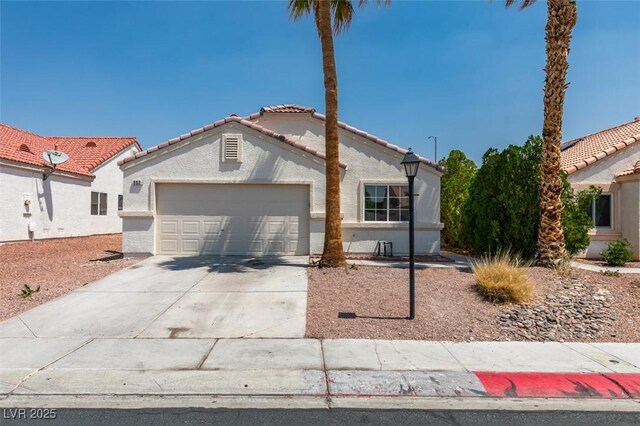 352 River Glider Ave, North Las Vegas, NV 89084 - view of front of house featuring a garage, concrete driveway, a tile roof, and stucco siding