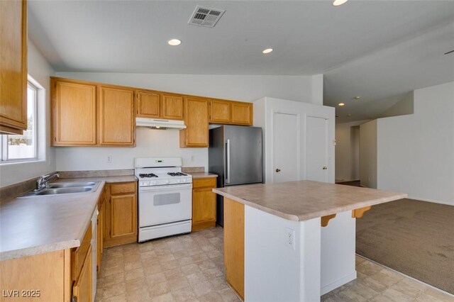 352 River Glider Ave, North Las Vegas, NV 89084 - kitchen featuring white range with gas stovetop, under cabinet range hood, freestanding refrigerator, vaulted ceiling, and a center island