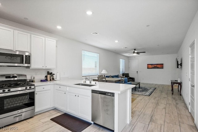 9740 Redwood Cascade St, Las Vegas, NV 89143 - kitchen featuring stainless steel appliances, a peninsula, ceiling fan, white cabinetry, and light countertops
