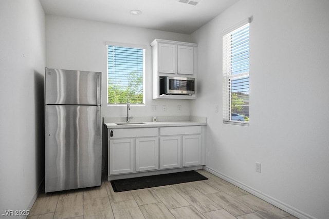 9740 Redwood Cascade St, Las Vegas, NV 89143 - kitchen with stainless steel appliances, healthy amount of natural light, light countertops, and white cabinetry