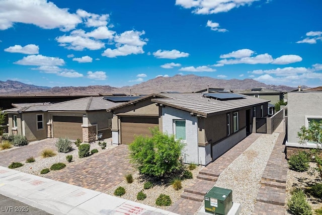 9740 Redwood Cascade St, Las Vegas, NV 89143 - view of front of home with stucco siding, a mountain view, roof mounted solar panels, an attached garage, and a tile roof
