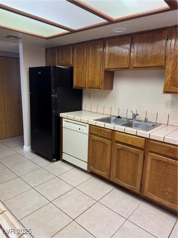 4231 Sanderling Cir Unit 267, Las Vegas, NV 89103 - kitchen with white dishwasher, tile counters, light tile patterned floors, and brown cabinetry