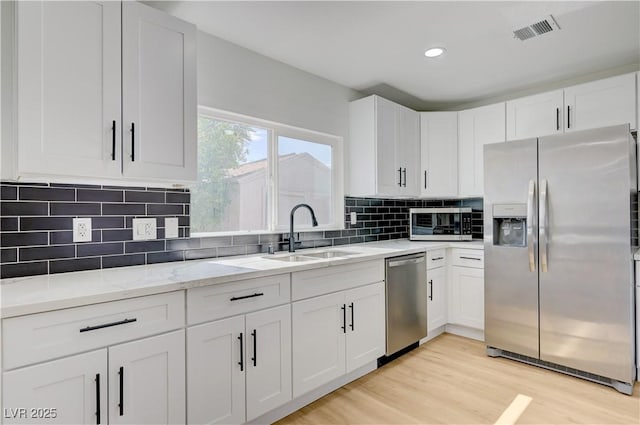 730 Arrowhead Trl, Henderson, NV 89002 - kitchen with stainless steel appliances, white cabinets, light wood-type flooring, decorative backsplash, and light stone countertops