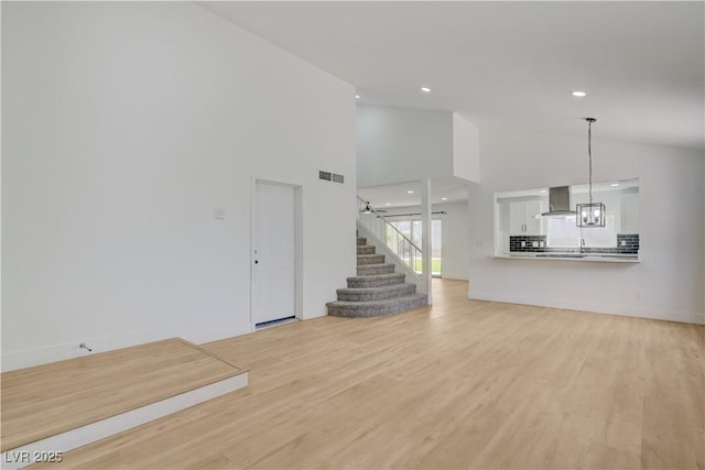 730 Arrowhead Trl, Henderson, NV 89002 - unfurnished living room featuring light wood-style flooring, recessed lighting, stairway, high vaulted ceiling, and a chandelier