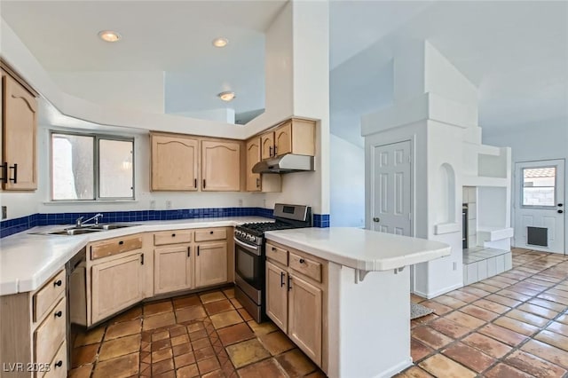 4616 Silversword Ave, North Las Vegas, NV 89032 - kitchen featuring stainless steel gas stove, a peninsula, light brown cabinetry, under cabinet range hood, and light countertops