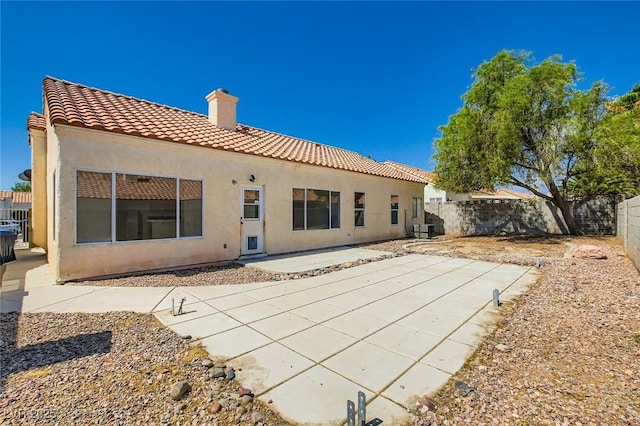 4616 Silversword Ave, North Las Vegas, NV 89032 - rear view of house featuring a chimney, a tile roof, stucco siding, a fenced backyard, and a patio area
