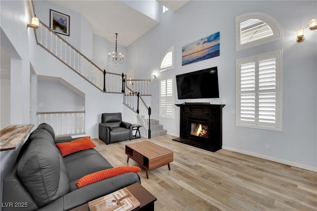3080 Yankee Clipper Dr, Las Vegas, NV 89117 - living room with a high ceiling, wood finished floors, stairs, a chandelier, and a warm lit fireplace