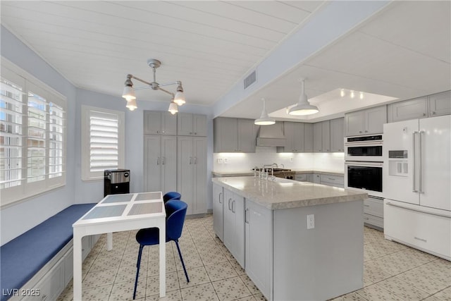 3080 Yankee Clipper Dr, Las Vegas, NV 89117 - kitchen featuring high end white fridge, double oven, gray cabinets, light countertops, and a center island with sink