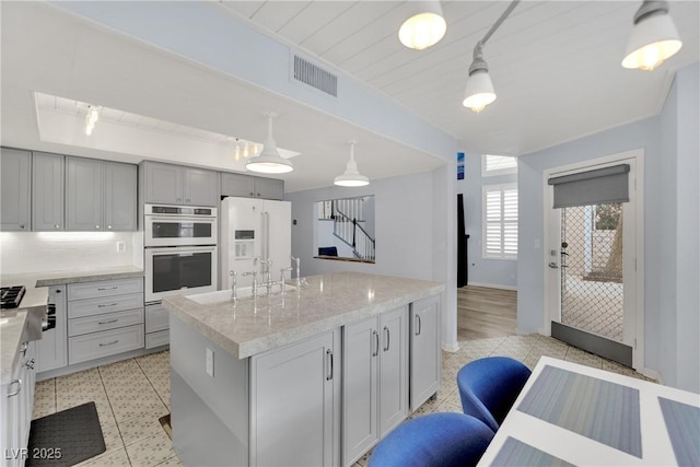 3080 Yankee Clipper Dr, Las Vegas, NV 89117 - kitchen featuring appliances with stainless steel finishes, a kitchen island, light stone counters, and decorative light fixtures