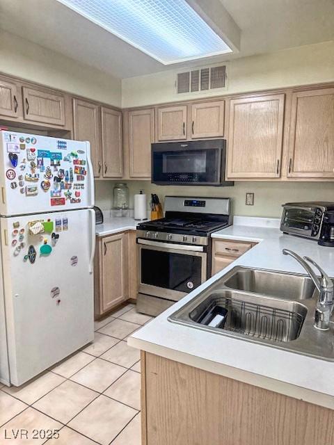 3101 Casey Dr Unit 204, Las Vegas, NV 89120 - kitchen with black microwave, freestanding refrigerator, stainless steel range with gas stovetop, light tile patterned floors, and light countertops