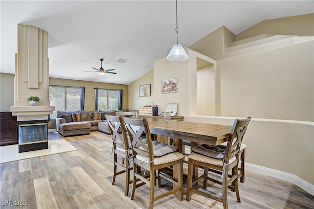 7401 Red Swallow St, Las Vegas, NV 89131 - dining room with vaulted ceiling, light wood-style flooring, a ceiling fan, and a glass covered fireplace