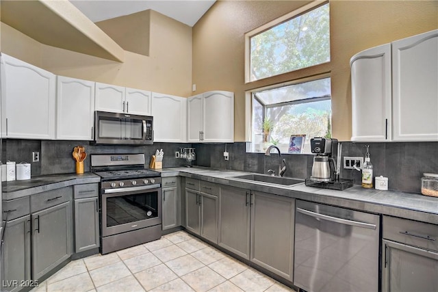 7401 Red Swallow St, Las Vegas, NV 89131 - kitchen featuring stainless steel appliances, gray cabinets, tasteful backsplash, a high ceiling, and light tile patterned floors