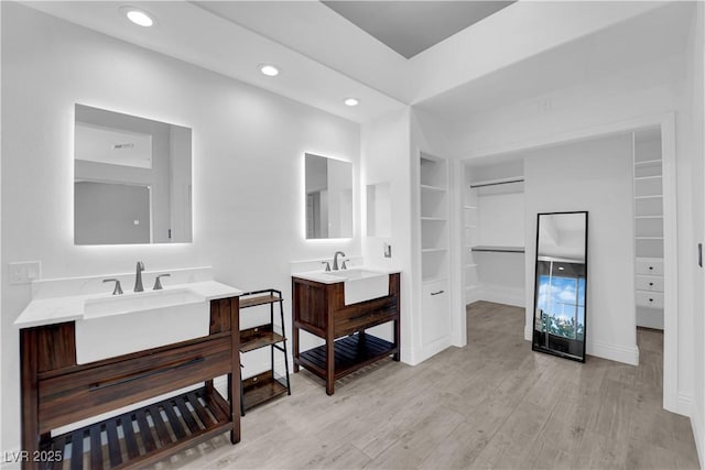56 Grossinger Ct, Henderson, NV 89074 - bathroom with two vanities, wood finished floors, built in shelves, a spacious closet, and recessed lighting