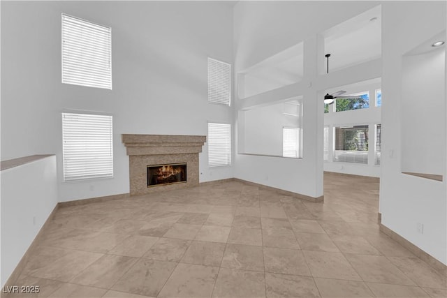 56 Grossinger Ct, Henderson, NV 89074 - unfurnished living room with a towering ceiling, ceiling fan, a glass covered fireplace, and light tile patterned floors