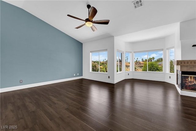 56 Grossinger Ct, Henderson, NV 89074 - unfurnished living room with lofted ceiling, a ceiling fan, a tiled fireplace, and dark wood-type flooring