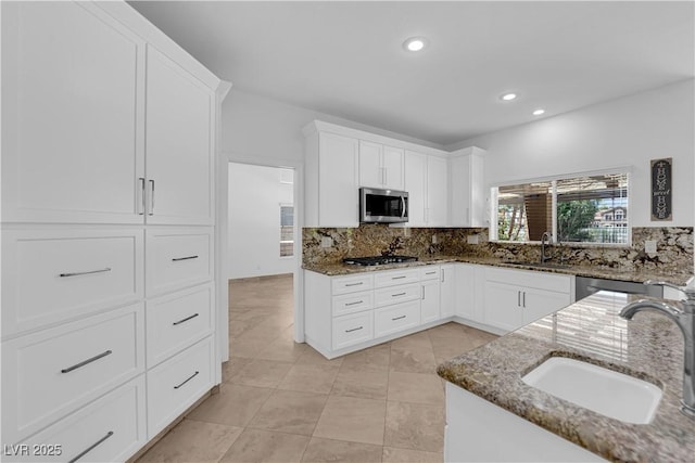 56 Grossinger Ct, Henderson, NV 89074 - kitchen with appliances with stainless steel finishes, backsplash, dark stone countertops, white cabinetry, and recessed lighting