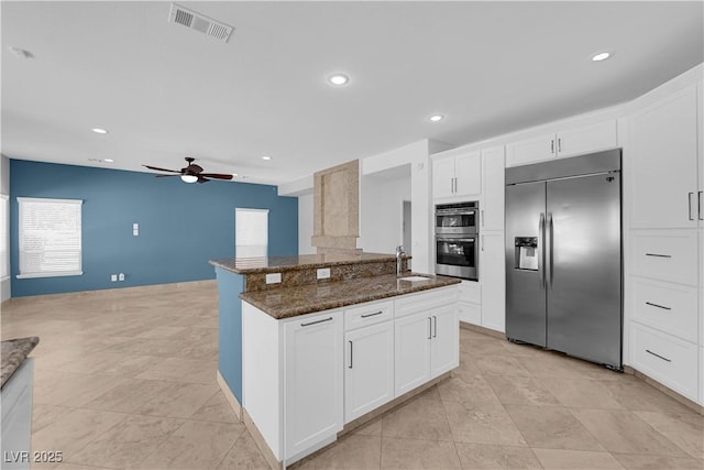 56 Grossinger Ct, Henderson, NV 89074 - kitchen featuring stainless steel appliances, a ceiling fan, dark stone counters, recessed lighting, and white cabinets
