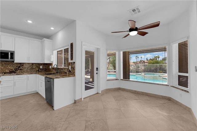56 Grossinger Ct, Henderson, NV 89074 - kitchen with stainless steel microwave, dishwasher, dark stone countertops, white cabinets, and a ceiling fan