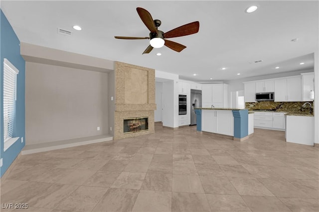 56 Grossinger Ct, Henderson, NV 89074 - kitchen with stainless steel appliances, open floor plan, a ceiling fan, a tile fireplace, and backsplash