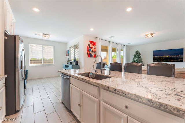 7107 Calvert Cliffs St, North Las Vegas, NV 89084 - kitchen featuring stainless steel appliances, light tile patterned floors, open floor plan, light stone countertops, and white cabinets