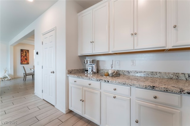 7107 Calvert Cliffs St, North Las Vegas, NV 89084 - kitchen with white cabinetry, light wood-style flooring, and light stone counters